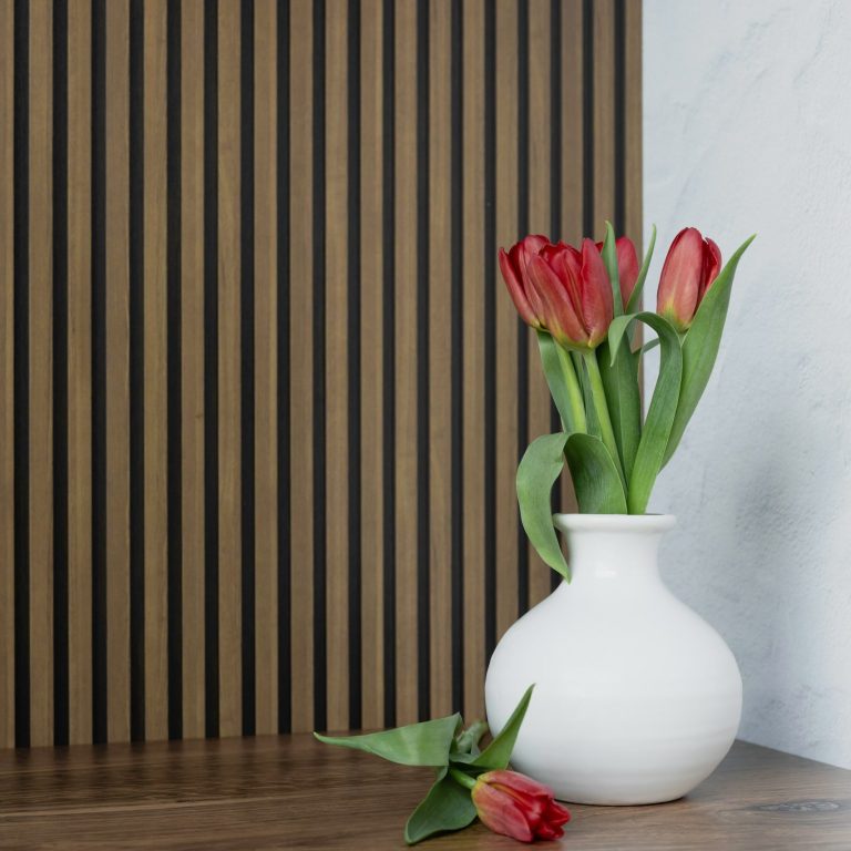Akustikpaneel mit Blumenvase Akustikpaneel im Hintergrund mit Blumenvase auf dem Tisch davor